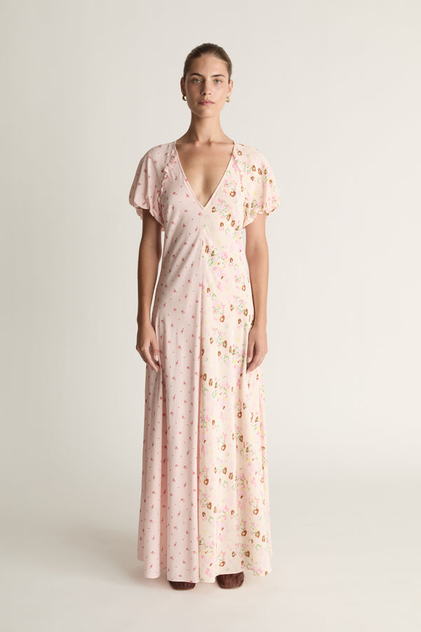 Woman wearing a light pink floral dress on a white background