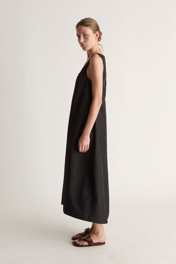 Side view of a sleeveless black midi dress with wide straps and a loose A-line shape.