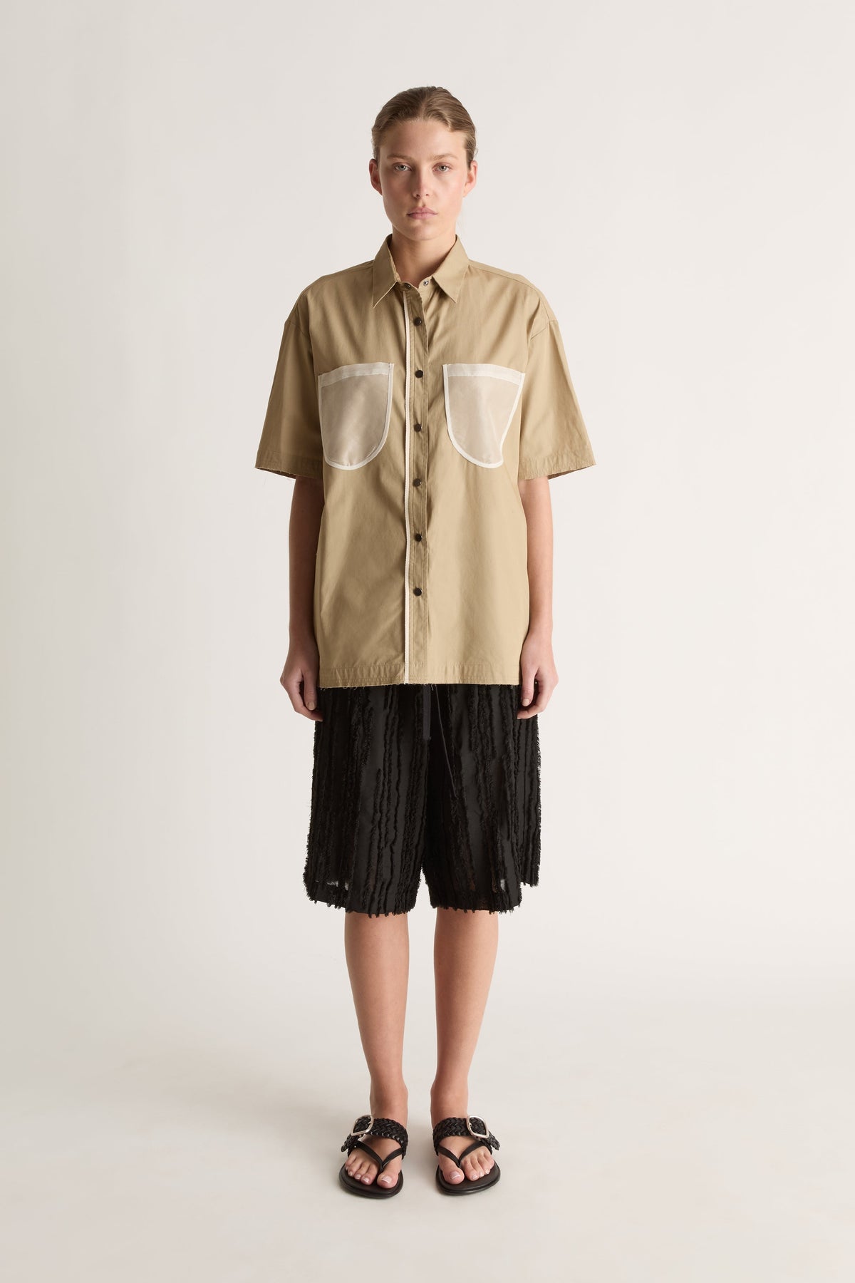 Front view of a camel short-sleeve button-up shirt with two sheer white chest pockets and white placket trim.