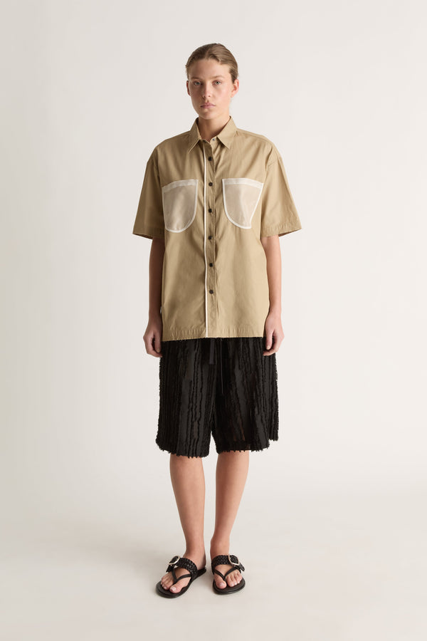 Front view of a camel short-sleeve shirt with a pointed collar, sheer chest pockets and dark buttons.