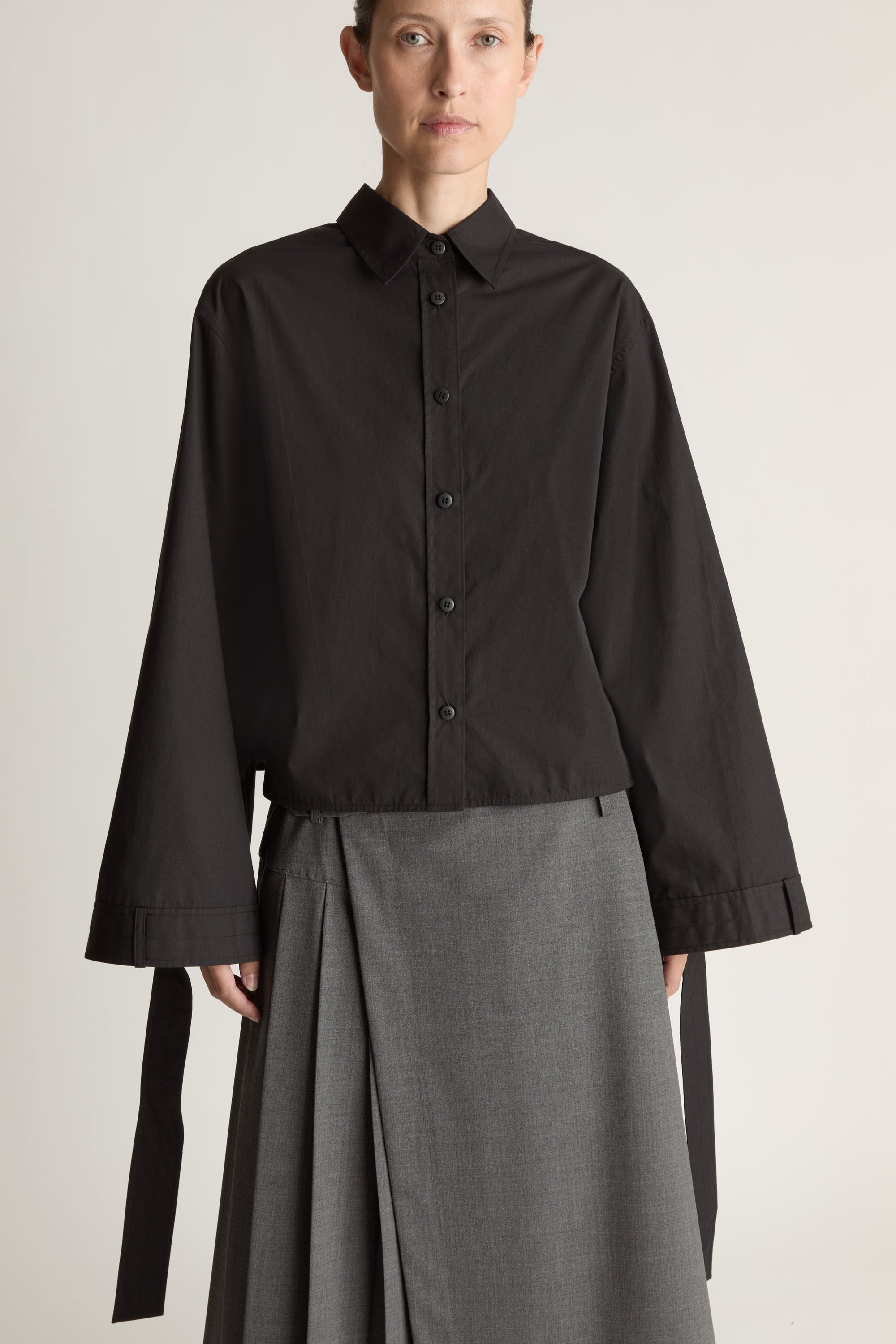 Person wearing a black shirt and gray skirt on a white background