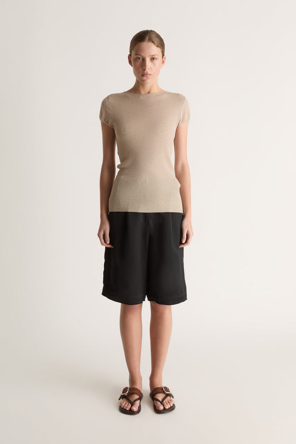 Front view of a woman wearing an oat knit tee and black bermuda shorts against a white studio background