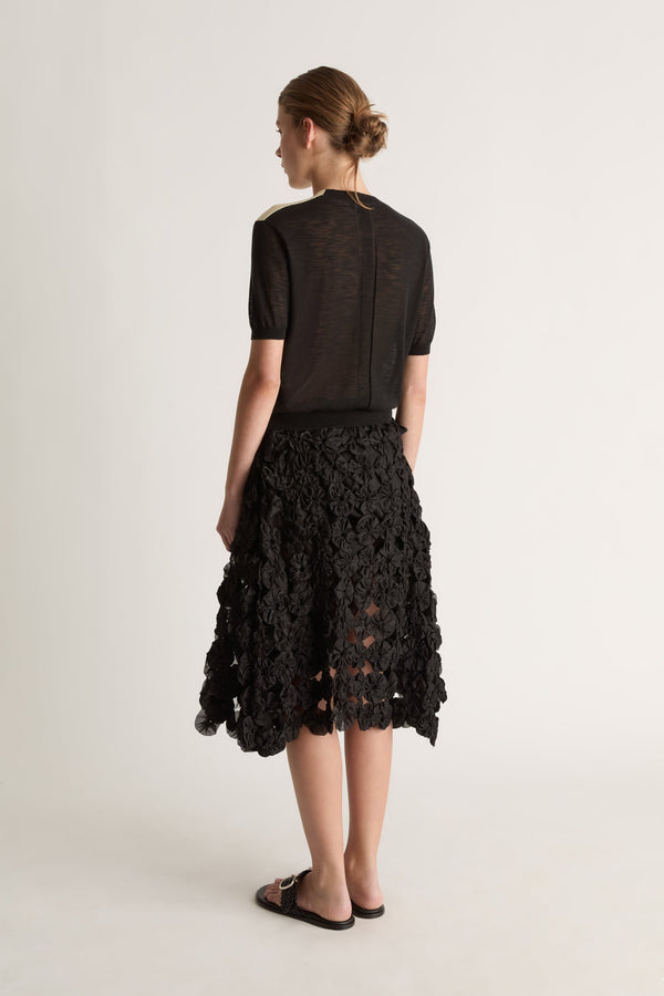 Back view of a short-sleeve black cardigan with a sheer, lightweight look and ribbed hem.