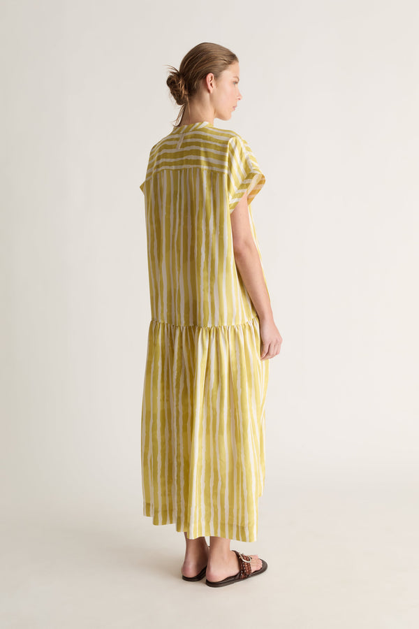 Back view of a woman with her hair up in a yellow striped silk dress with yoke seam and tiered skirt