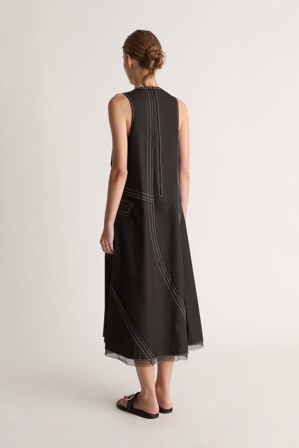 Back view of a sleeveless black midi dress with white topstitched seams and a back neck opening.
