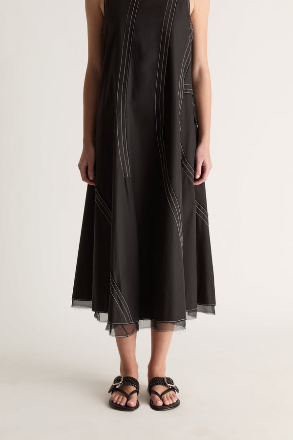 Close-up front view of a black dress skirt with white contrast topstitching and a sheer layered hem.