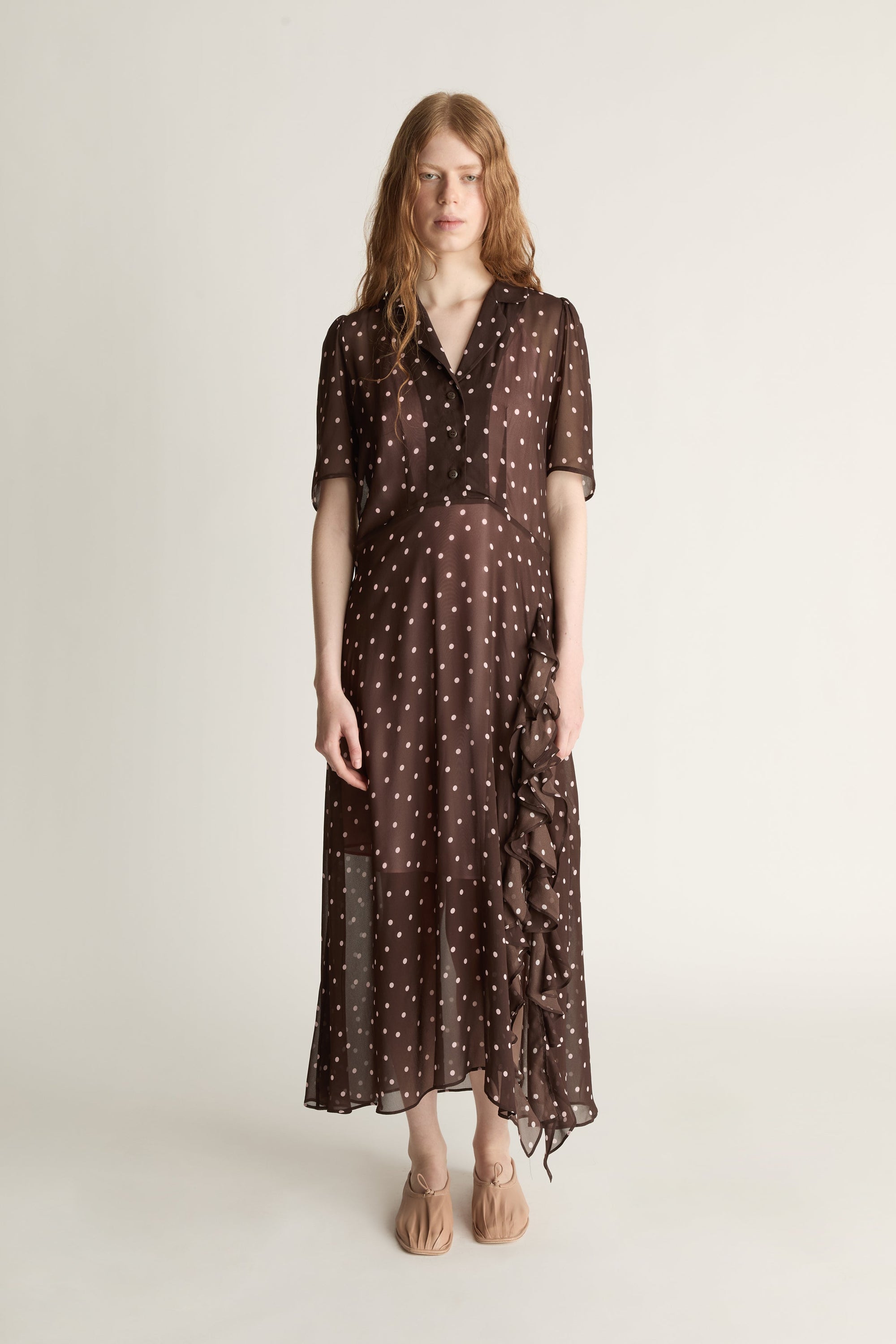 Woman wearing a brown polka dot dress on a white background