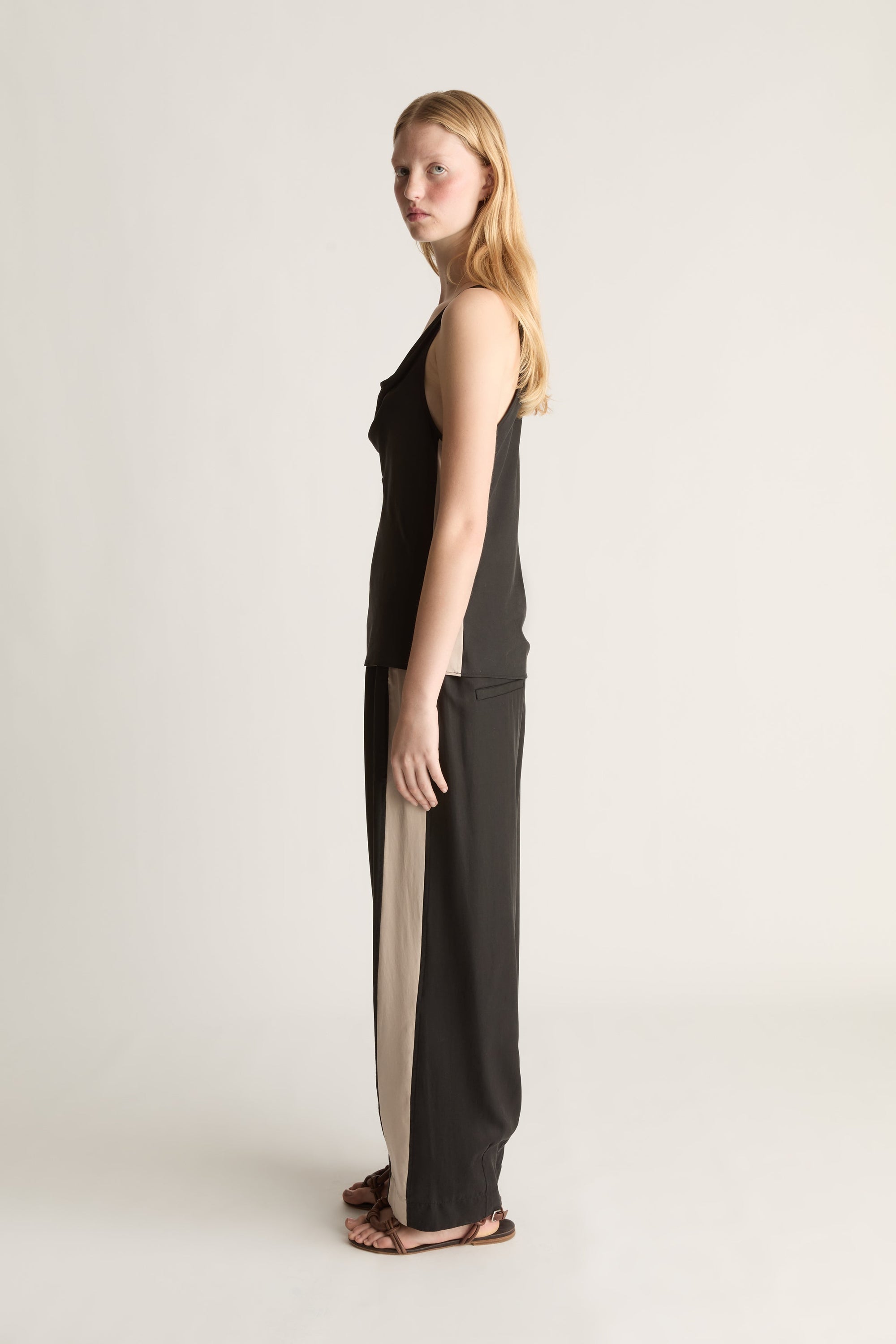 Woman wearing a black sleeveless top and pants on a plain background