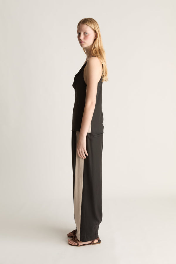 Woman wearing a black sleeveless top and pants on a plain background