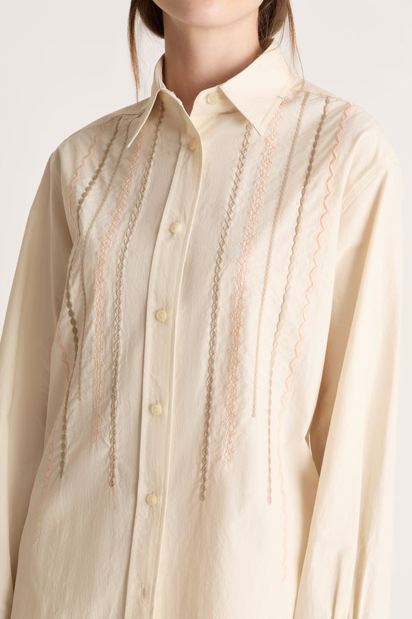 Close-up of a beige shirt with intricate detailing on a white background