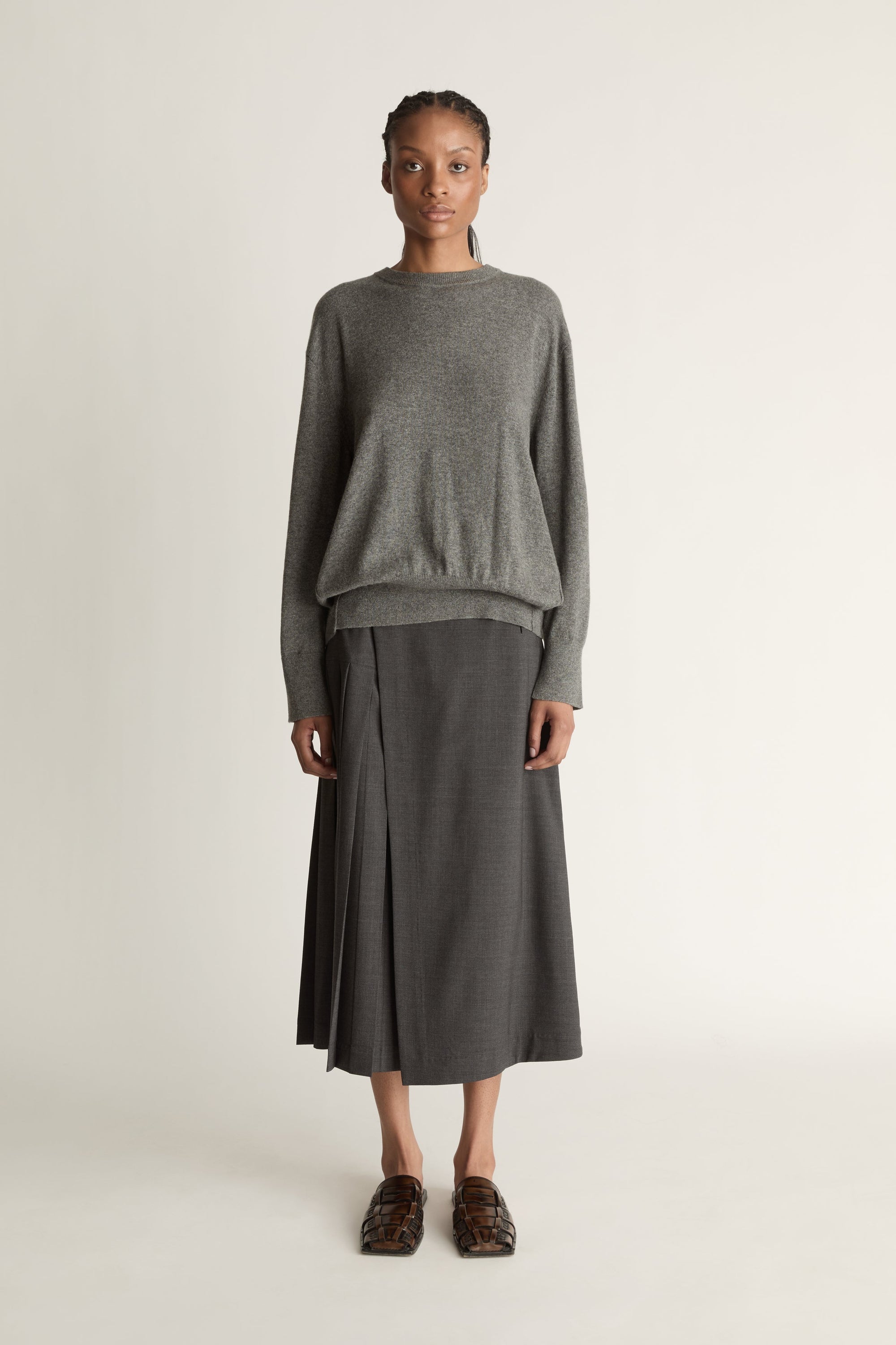 Woman wearing a gray sweater and skirt on a white background
