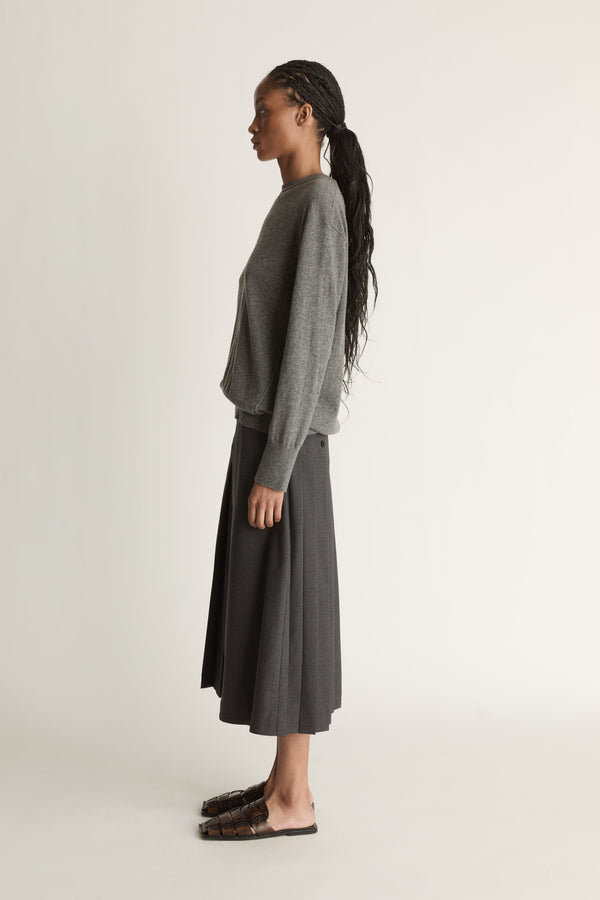 Woman wearing a gray sweater and dark gray skirt on a white background