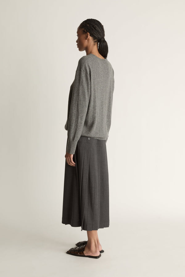 Woman wearing a gray sweater and dark gray skirt on a white background