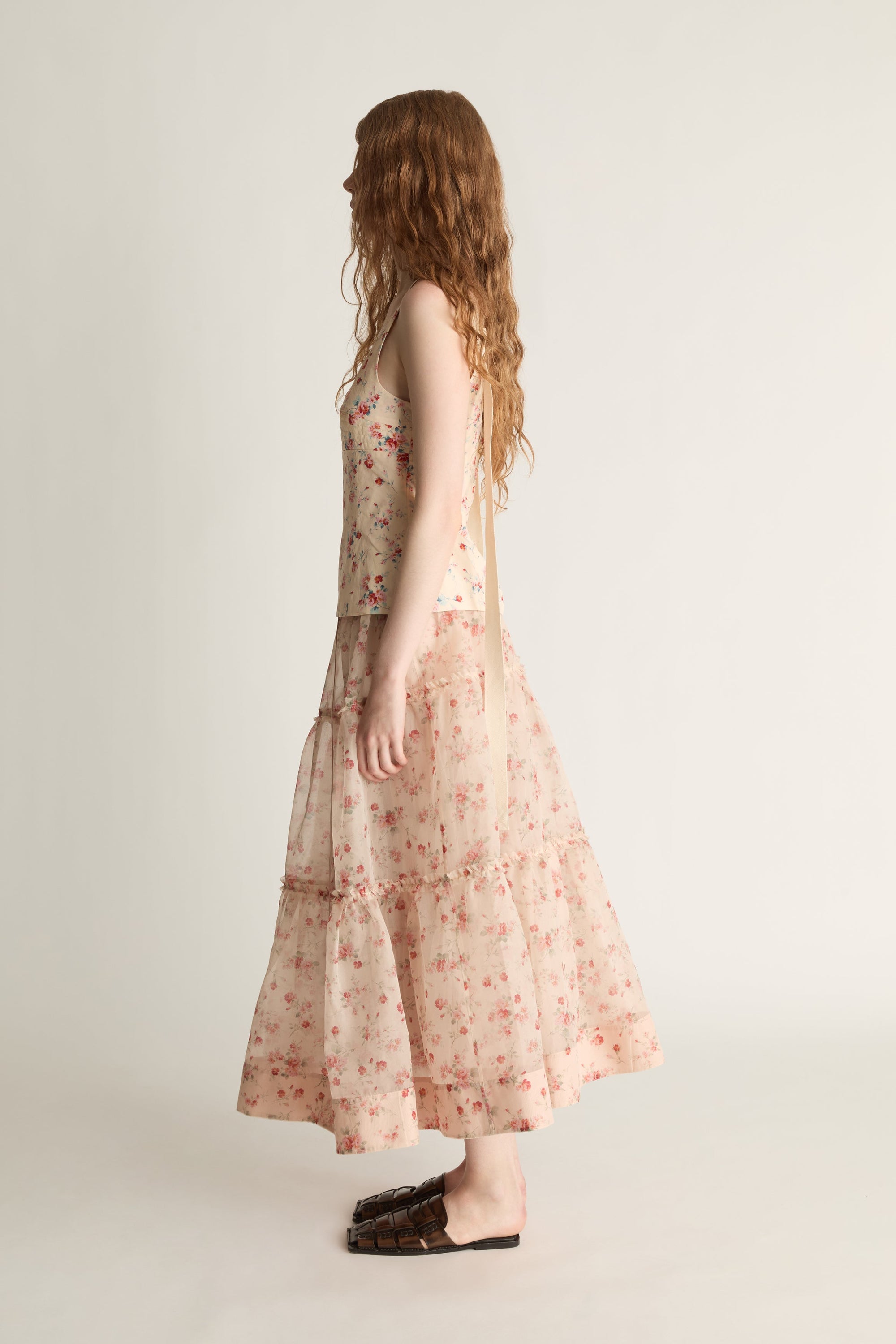 A woman wearing a floral top and skirt on a plain background