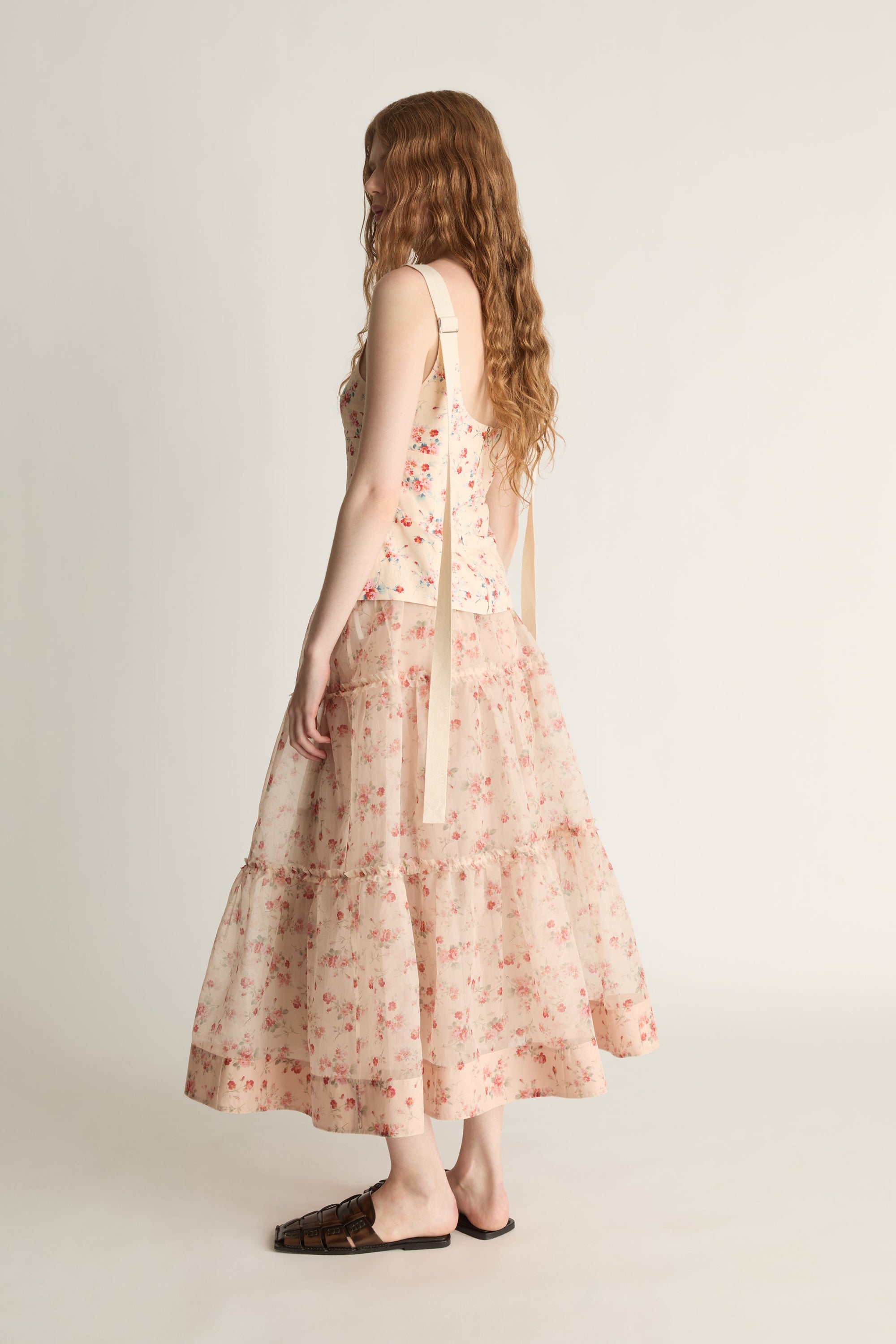 A woman wearing a floral top and skirt on a plain background