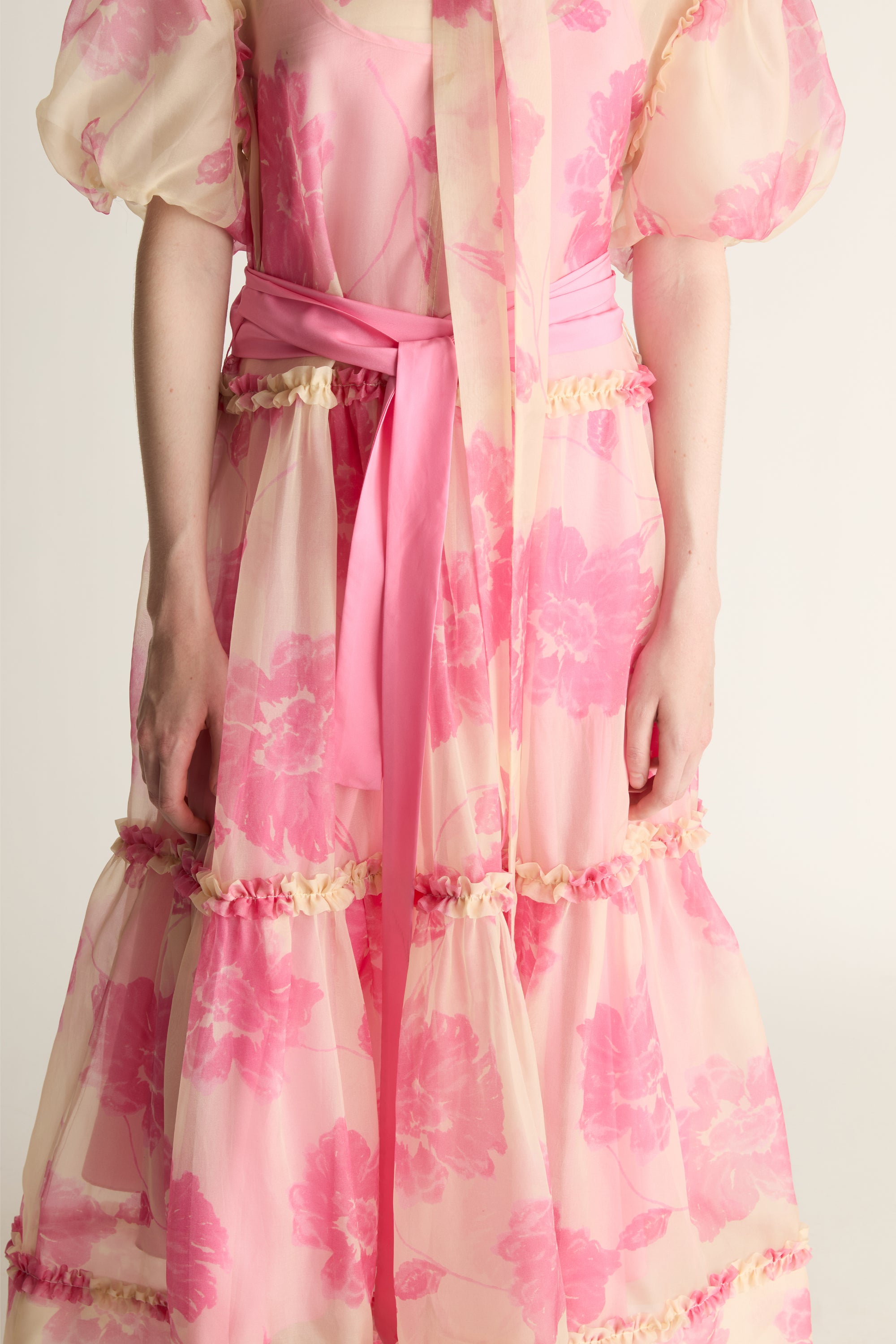 Pink floral dress with a belt on a plain background