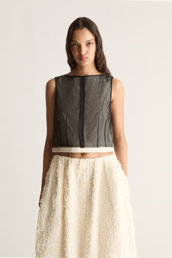 Close-up front view of a cropped sleeveless sheer black top with a centre seam and cream hem band.
