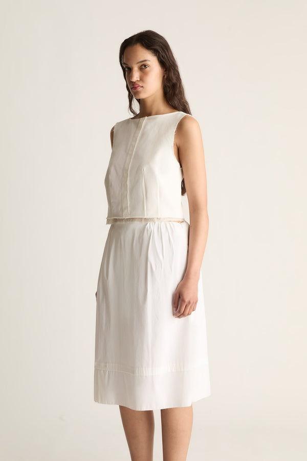 Angled front view of a cropped sleeveless cream top with a centre front seam and frayed hem.