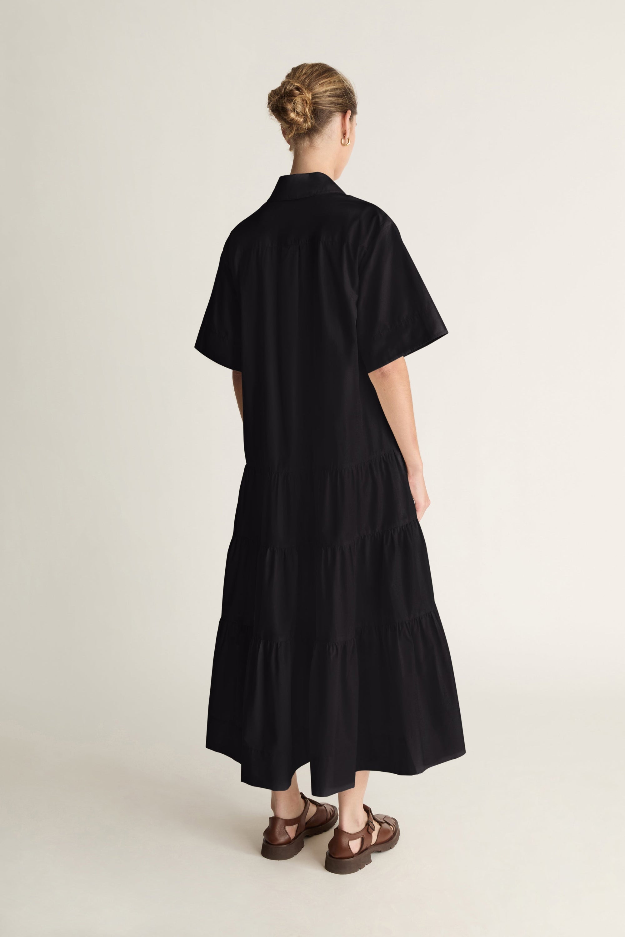 Person wearing a black dress standing against a white background