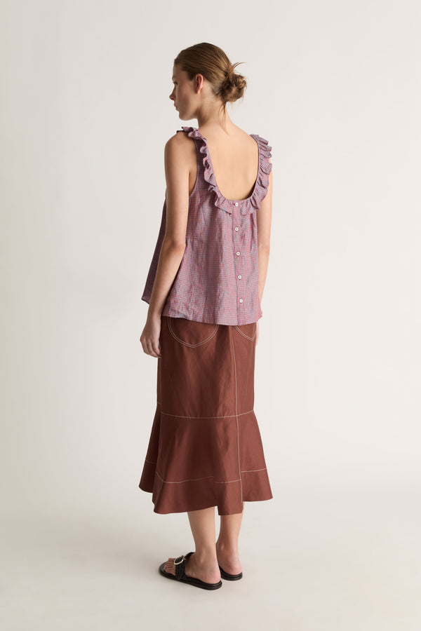 Back view of a woman with a bun in a plum check cami top with scoop back and button closure, and a brown skirt