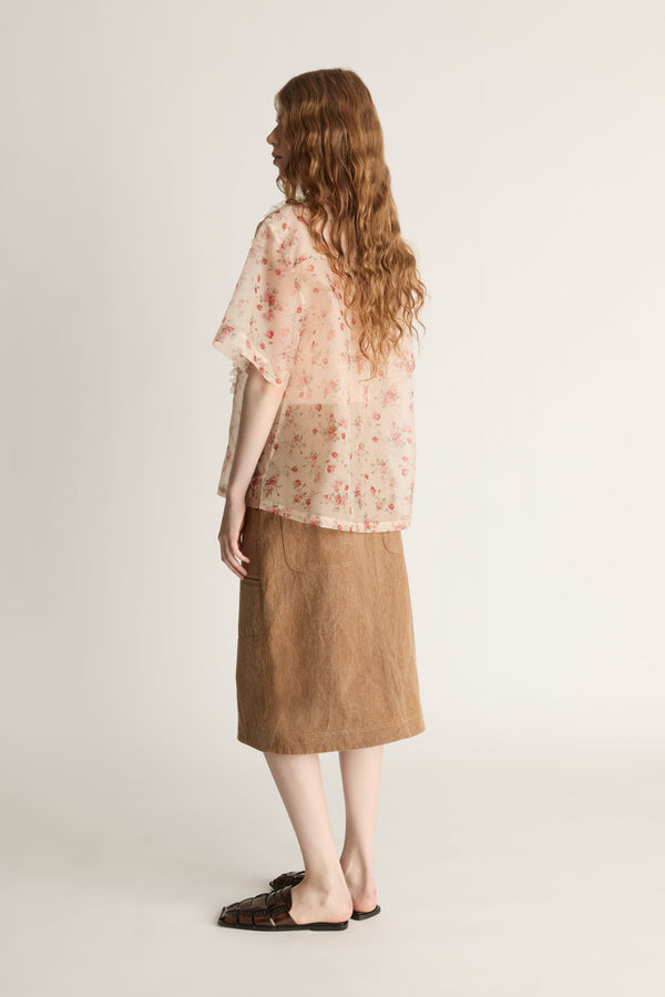 Person wearing a floral blouse and brown skirt on a white background