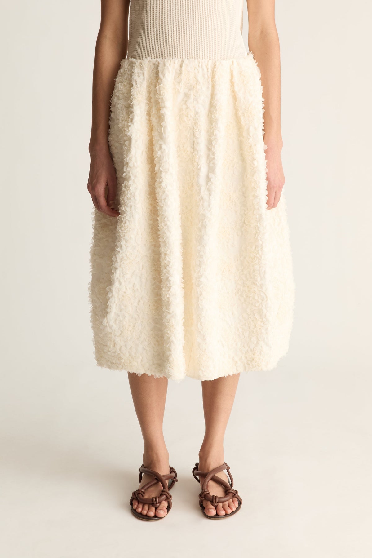 Close-up of a cream tufted cocoon midi skirt with gathered waist and rounded hem