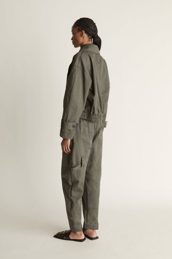 Person wearing a green coat and pants on a plain background