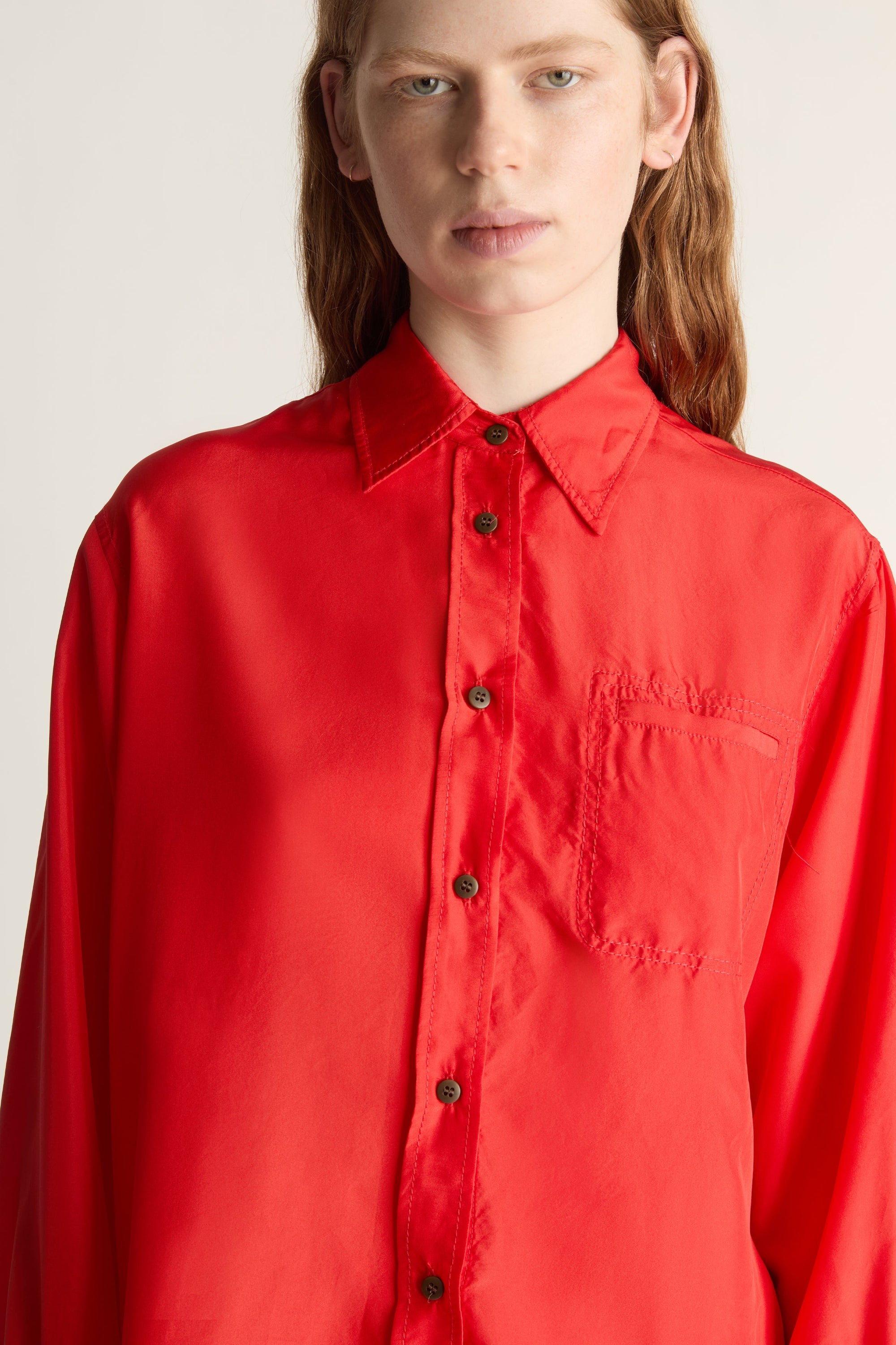 Person wearing a red shirt and patterned skirt on a plain background