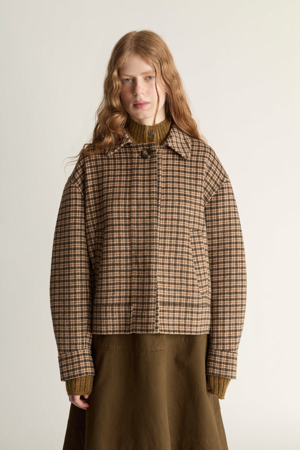 Woman wearing a plaid jacket and brown skirt on a white background