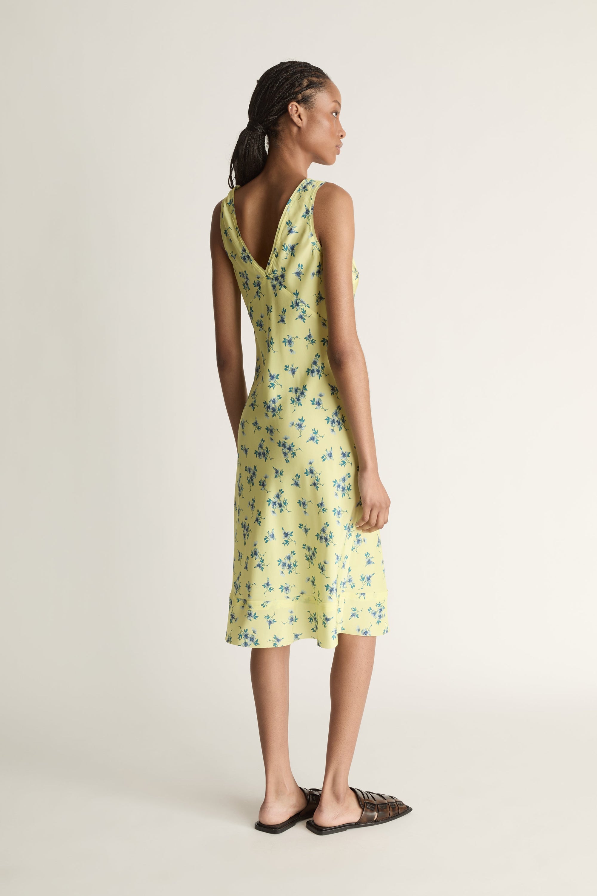 Woman wearing a yellow floral dress on a white background