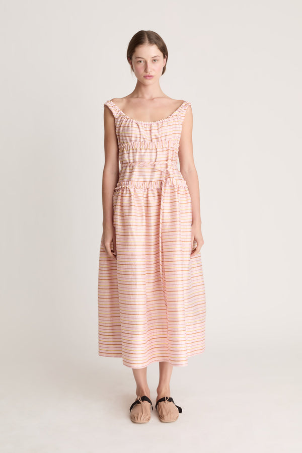 Woman wearing a sleeveless dress with a striped pattern on a plain background