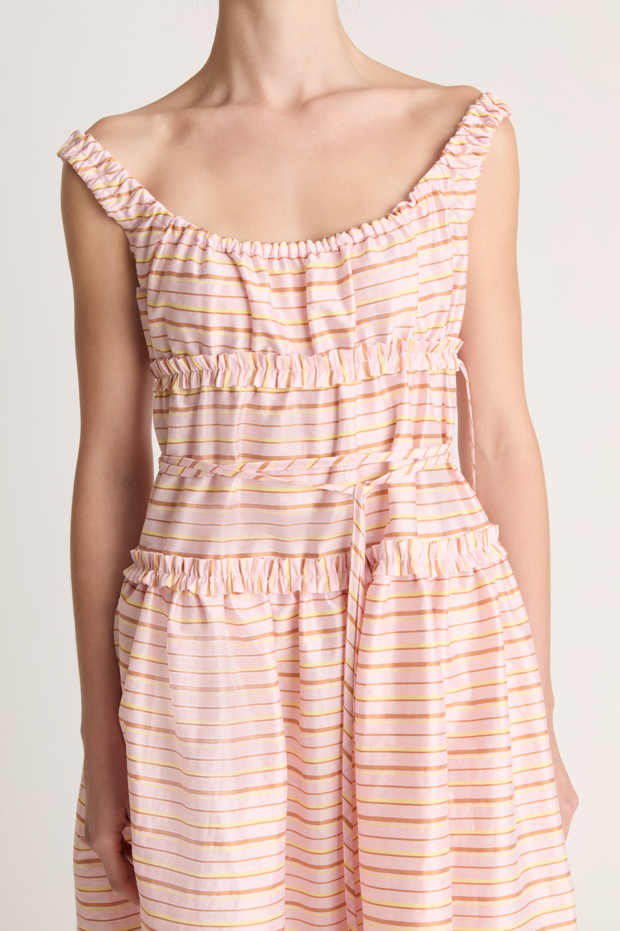 Woman wearing a sleeveless dress with a striped pattern on a plain background