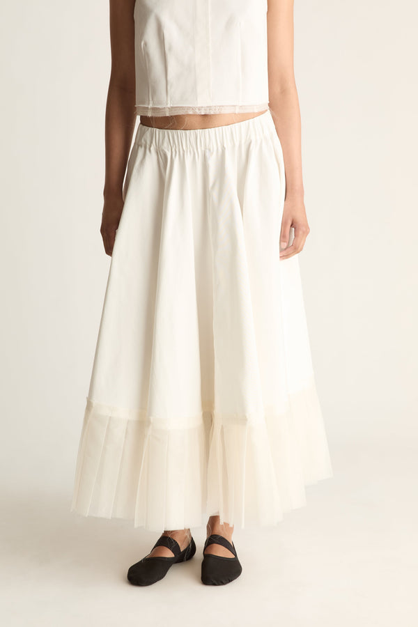 Close-up front view of a cream skirt with an elasticated waist, flared shape and sheer layered hem.