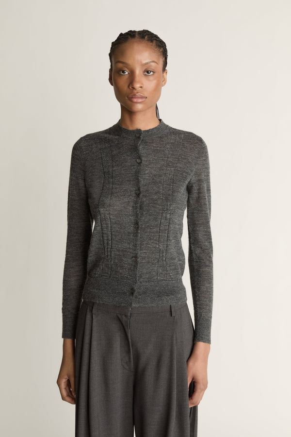 Woman wearing a grey cardigan and grey trousers on a white background