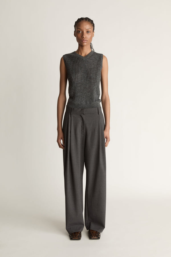 Woman wearing a sleeveless knitted top and wide-leg pants on a plain background