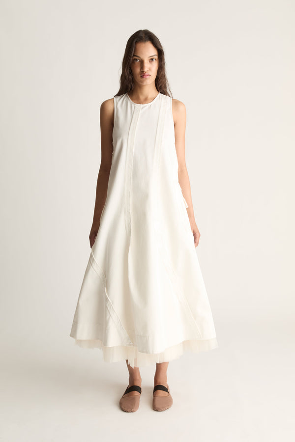 Front view of a woman wearing a white sleeveless A-line midi dress against a white studio background