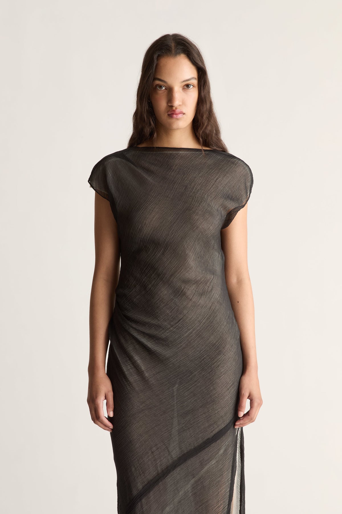 Close-up of a sheer black dress with boatneck, ruched side and diagonal seam
