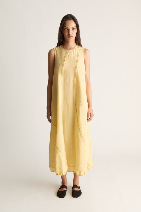 Front view of a woman wearing a yellow sleeveless midi tank dress with seam detail against a white studio background