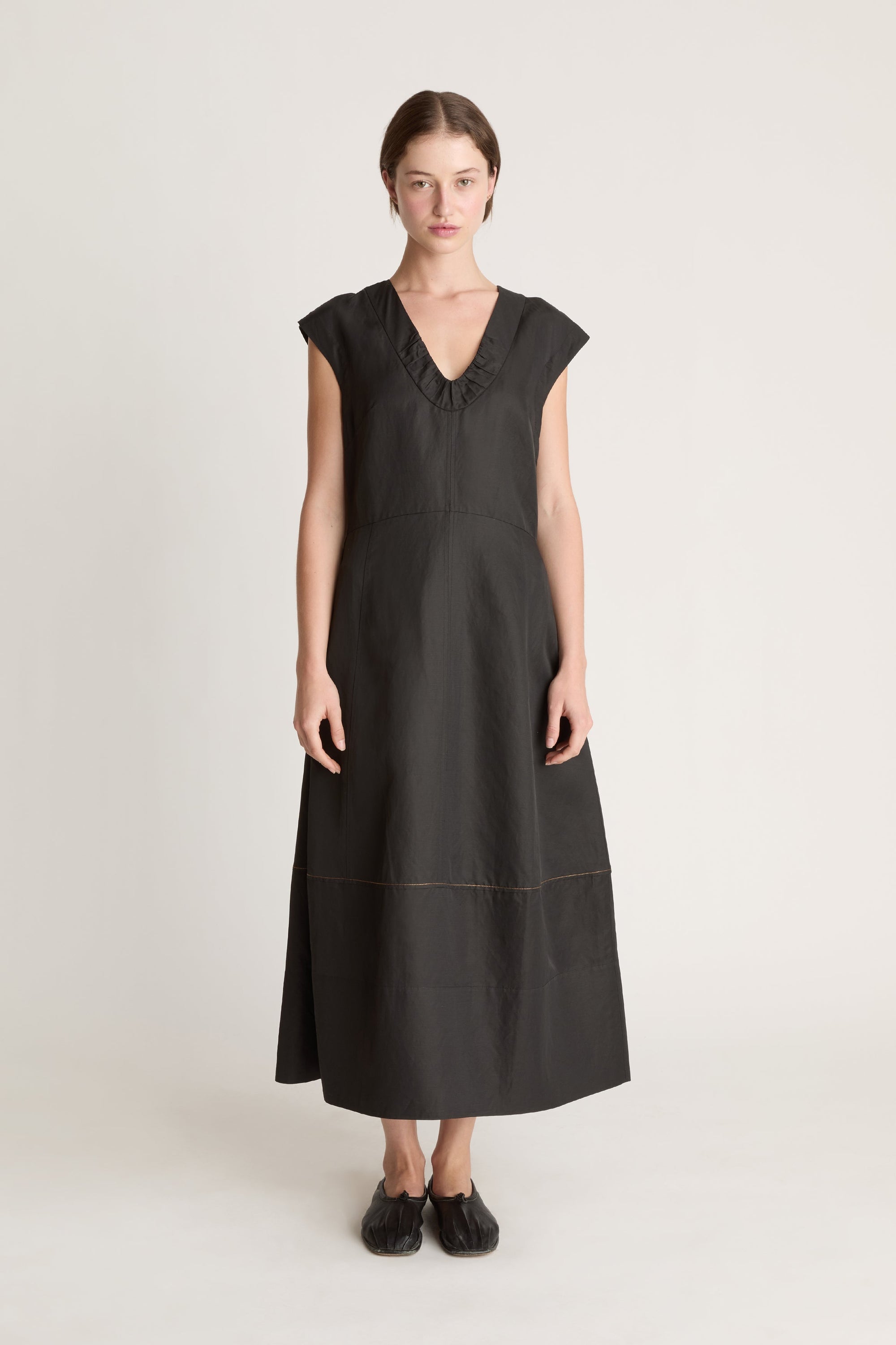 Woman wearing a black  v neck dress on a white background
