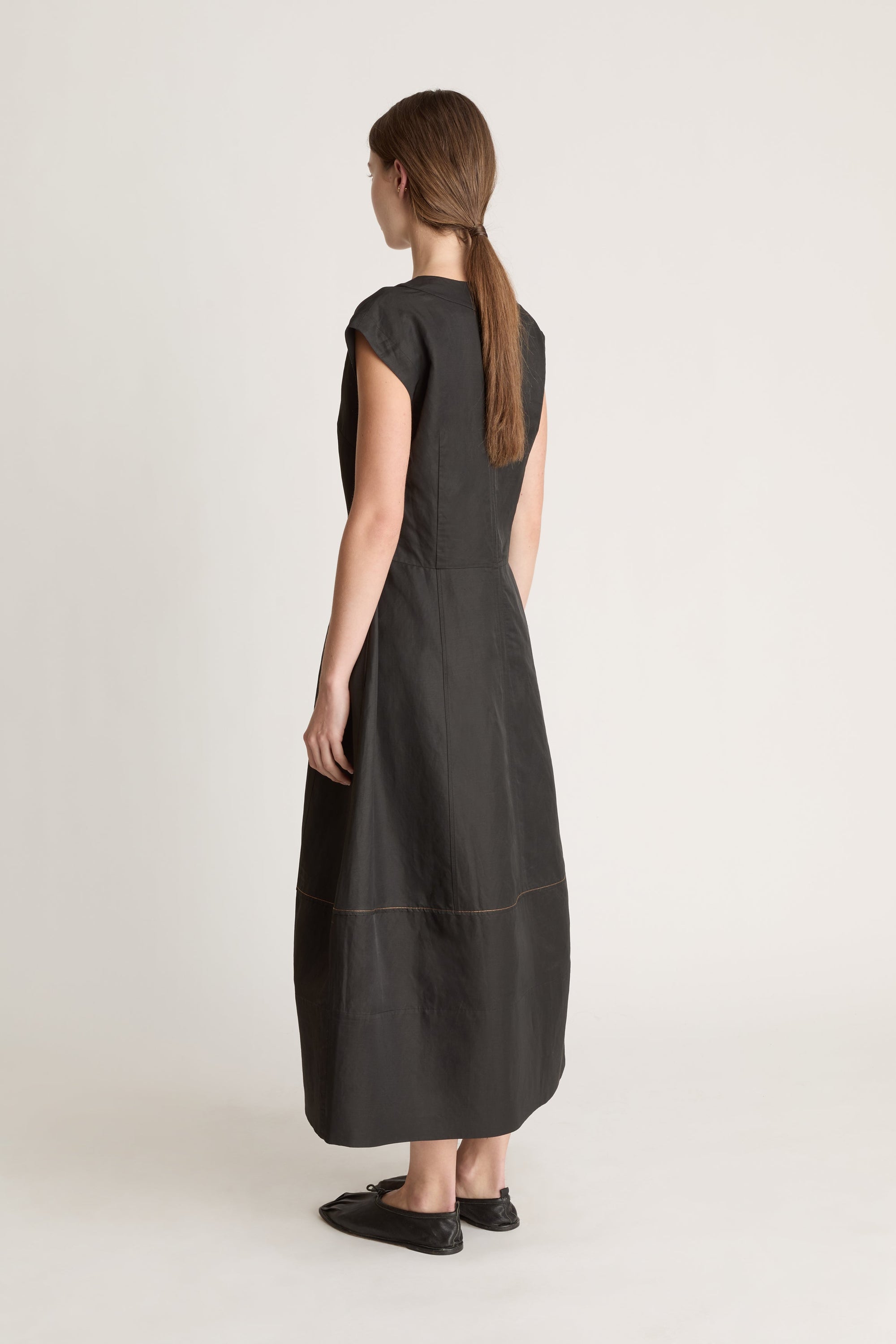 Woman wearing a black  v neck dress on a white background