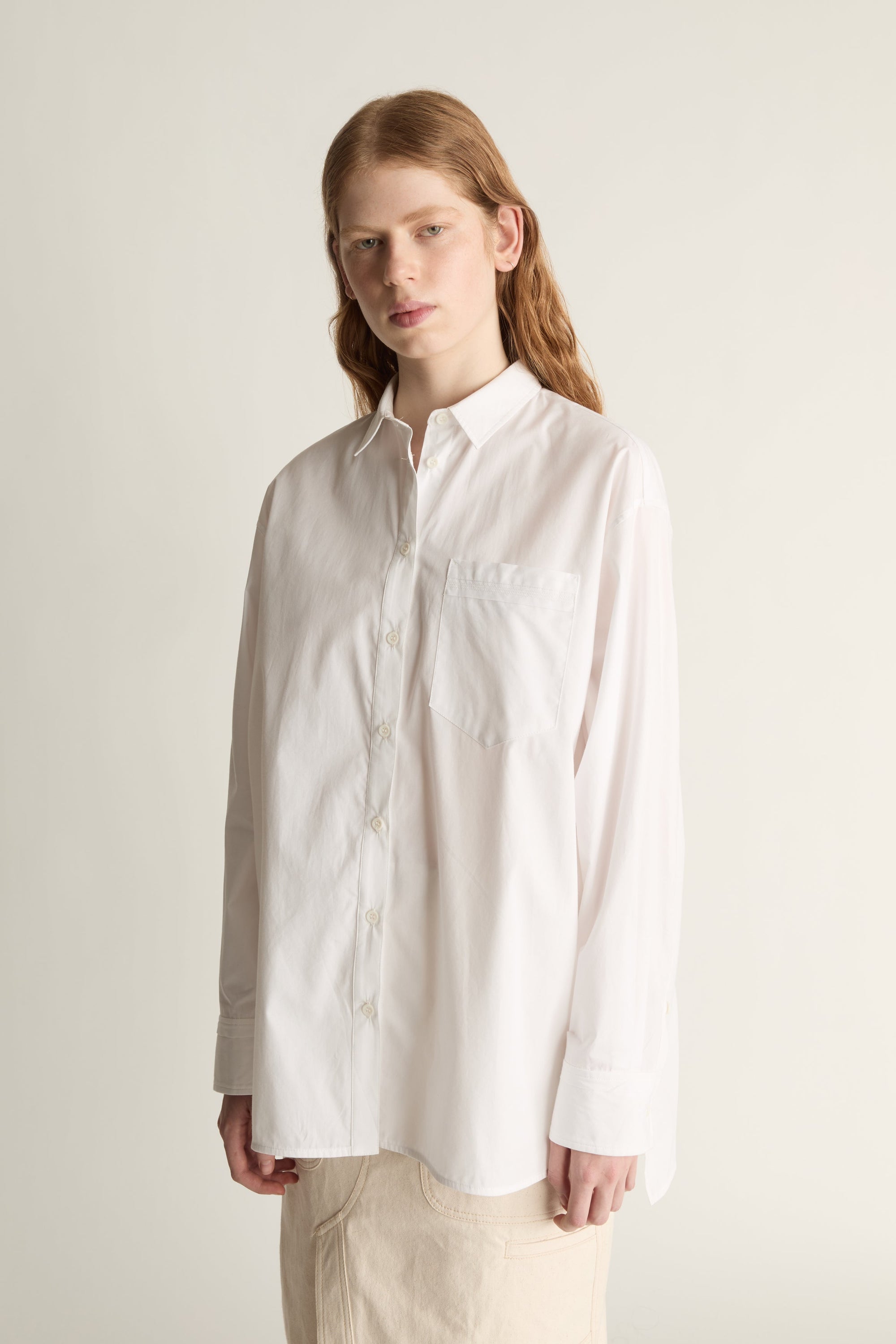 Person wearing a white shirt and beige skirt on a plain background