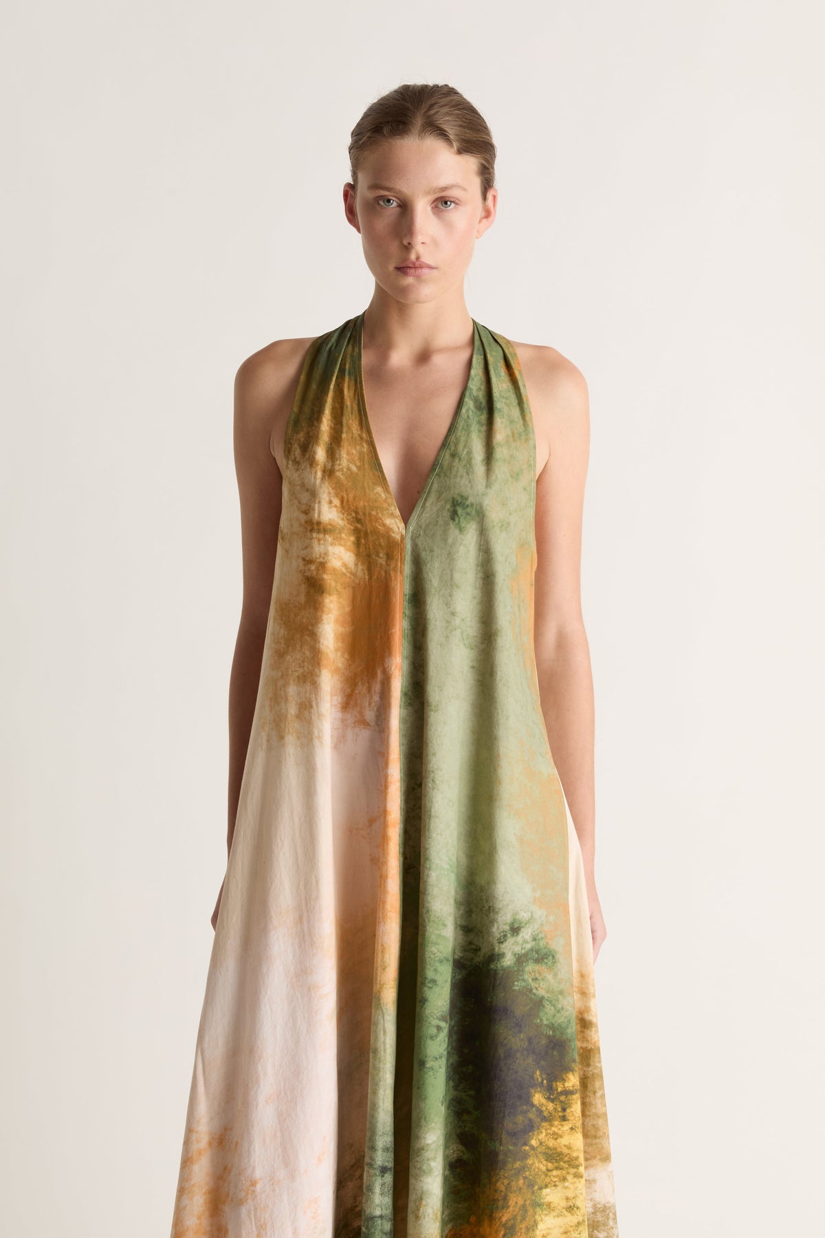 Close-up of a deep V-neck halter dress with a green, ochre and charcoal watercolour print