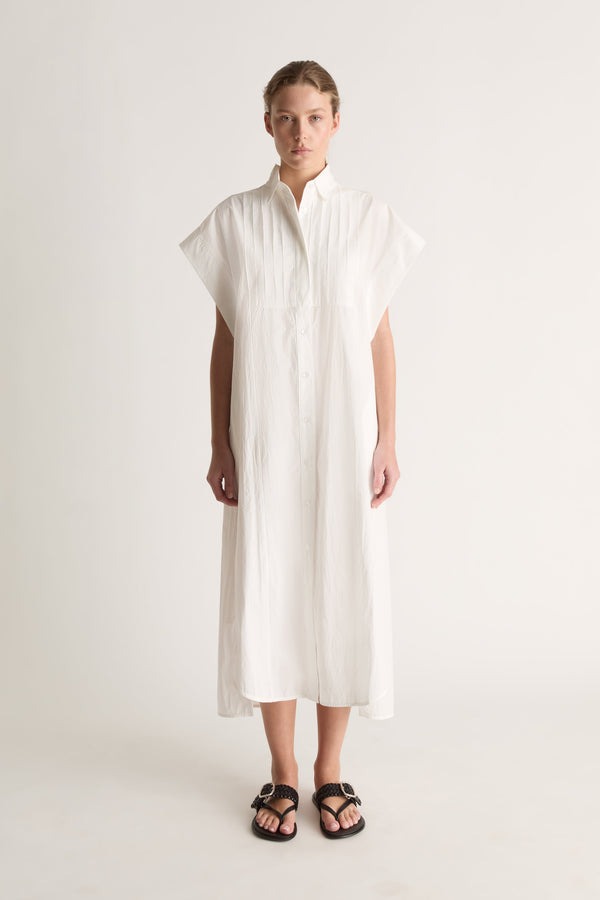 Front view of a white midi shirt dress with wide cap sleeves, a pin-tucked bib and button front.