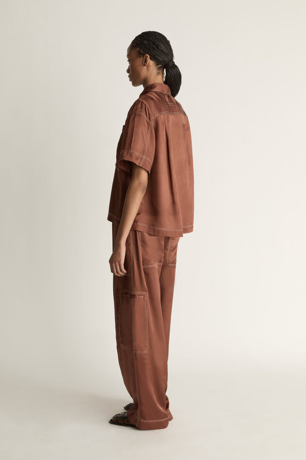Person wearing a brown shirt and pants on a plain background
