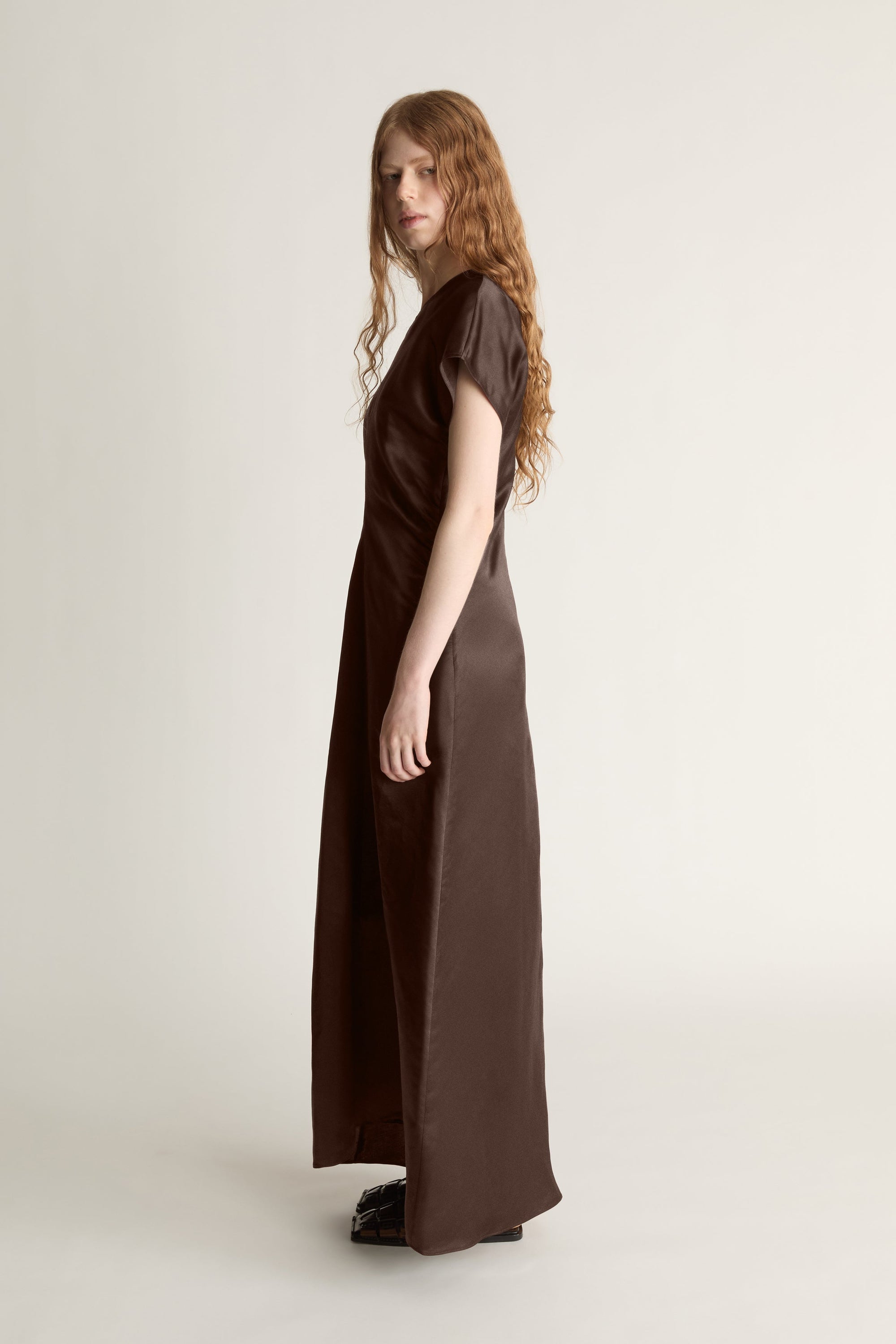 Woman wearing a brown dress against a plain background