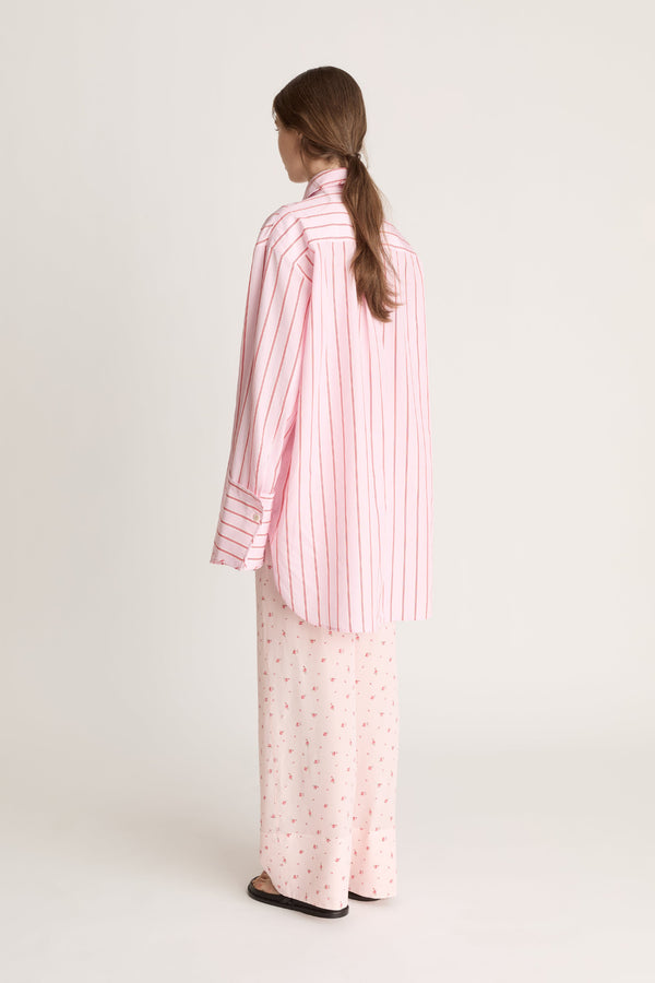 Woman wearing a pink striped shirt and pink floral pants on a white background