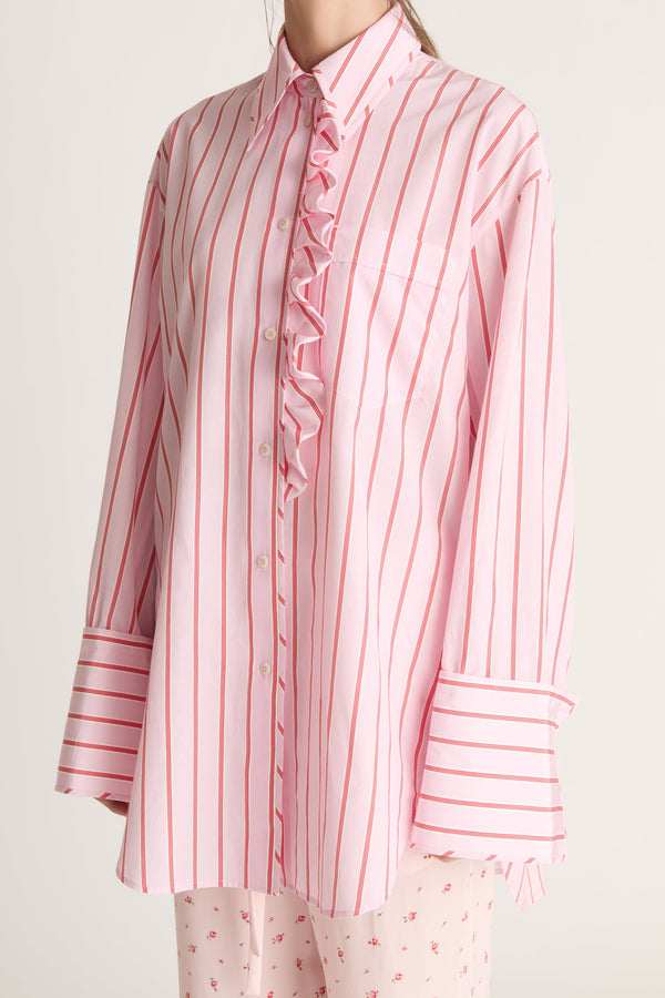 Woman wearing a pink striped shirt and pink floral pants on a white background
